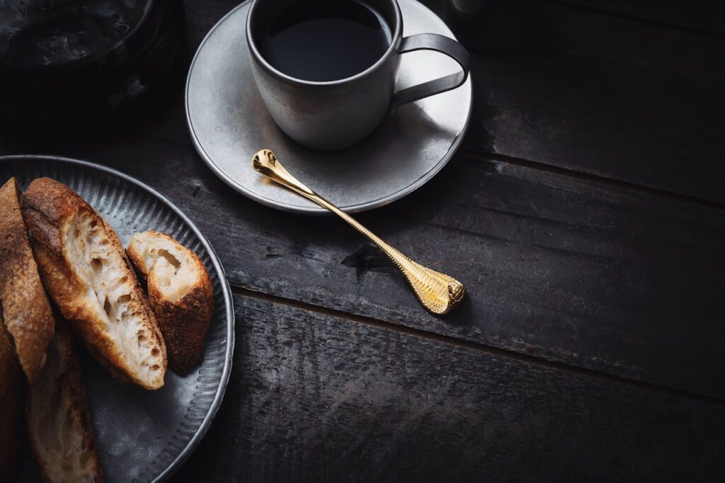 Moody setup with dark coffee and artisan bread on a vintage table.