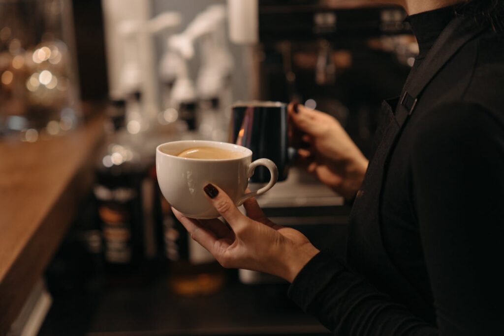 Close-up of a barista making coffee, highlighting latte art and cozy café atmosphere.